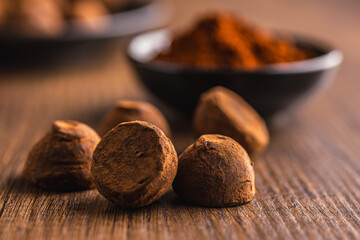 Chocolate truffles covered with cocoa powder on wooden table.
