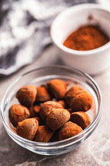 Chocolate truffles covered with cocoa powder in bowl on kitchen table.