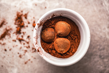 Chocolate truffles covered with cocoa powder in bowl on kitchen table.Top view.