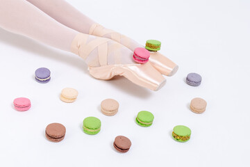 ballerina's legs in pointe shoes and bright sweets macaron cake. Dance and health choice concept