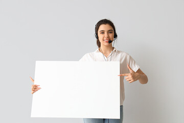 Female technical support agent with blank poster on light background