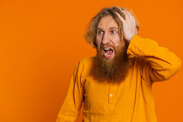 Irritated angry Caucasian man screams from stress tension problems feels horror hopelessness fear surprise shock expresses rage nervous quarrel. Redhead guy isolated on orange background. Copy-space