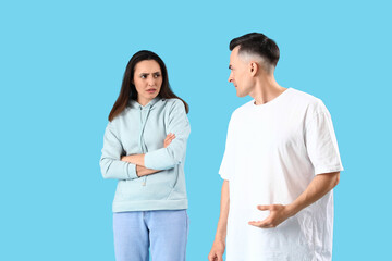 Offended young woman with her husband on blue background