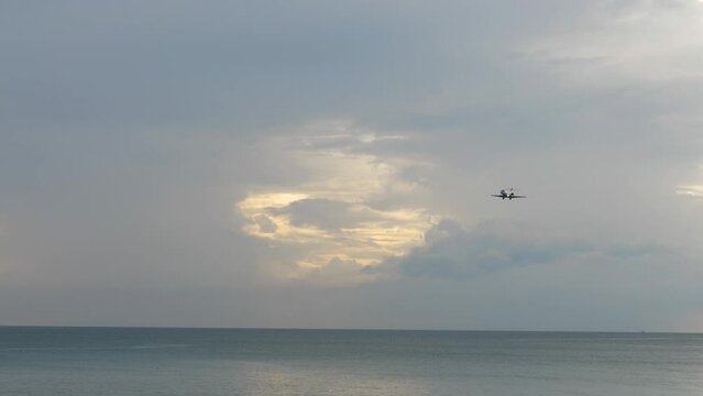 Air plane fly over the blue sea at Phuket, Thailand. Aircraft approaching before landing, descending. Cloud landscape, sunset
