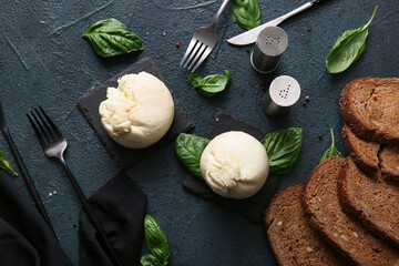 Tasty Burrata cheese with basil and bread on dark background