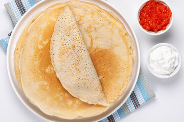 Pancakes with red caviar and sour cream, Close-up of pancakes stacked on white background
