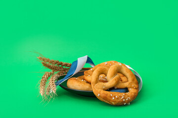 Plate with tasty pretzels on green background. Oktoberfest celebration