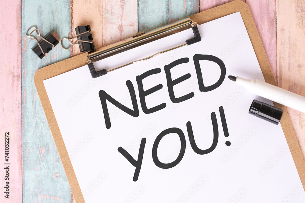 Poster need you text written on notebook page. office desk table top view