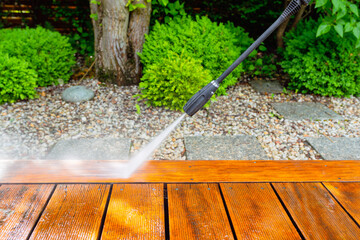 cleaning terrace with a power washer - high water pressure cleaner on wooden terrace surface - shallow depth of field