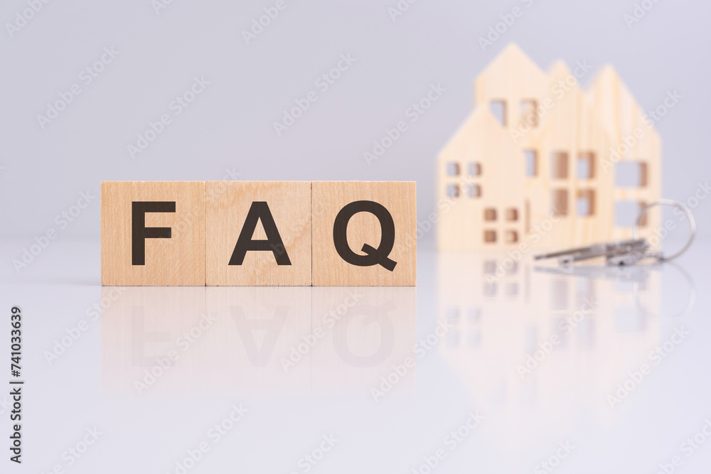Poster close-up of wooden blocks with the text faq and a toy wooden house with keys on a gray background. s
