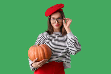 Beautiful young woman with pumpkin on green background