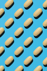 yellow pills on a blue background with white. Preparation on the topic of medicine and health
