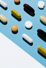 many different pills on a blue background with a white area. Preparation on the topic of medicine and health