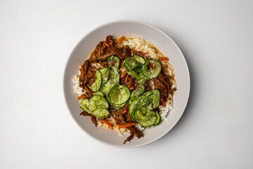 Colorful asian dish with white rice carrots mushrooms and cucumber slices with some white sesame