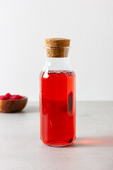 Raspberry drink in the glass bottle on the light background.
