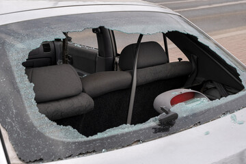 The rear window of a car shattered and removed, items were stolen. Crime scene.