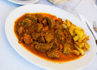 Appetizing baked pork cheeks served with potato and vegetables on plate