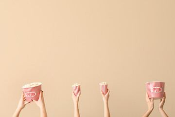 Hands holding buckets with popcorn on beige background