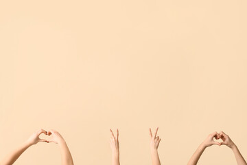 Female hands showing peace and heart gestures on beige background
