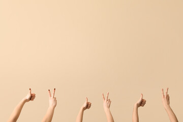 Female hands showing peace and thumb-up gestures on beige background
