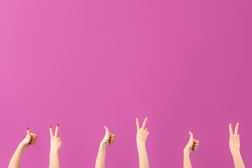 Female hands showing peace and thumb-up gestures on purple background