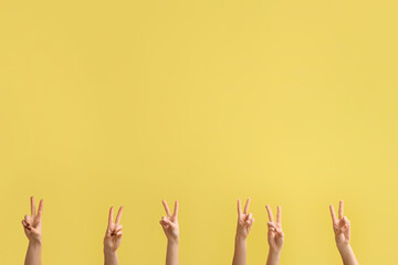 Female hands showing peace gestures on yellow background
