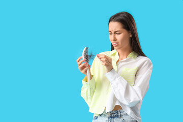 Worried young woman with hair loss problem on blue  background