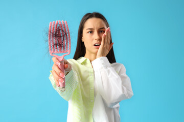 Shocked young woman with hair loss problem on blue  background