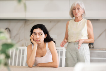 Elderly woman during family quarrel with young woman in kitchen at home