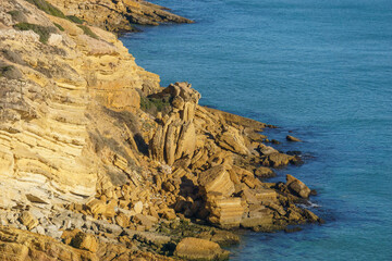 Rock formation of the coast cliffs in front of the atlantic sea in golden sunlight at Figueira...