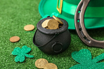 Pot with golden coins, horseshoe and leprechaun hat on grass. St. Patrick's Day celebration
