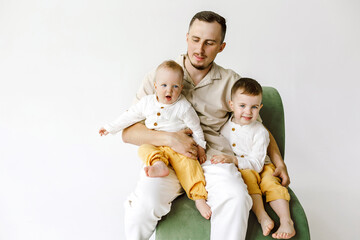 happy dad with two children boys in yellow pants on a white background.