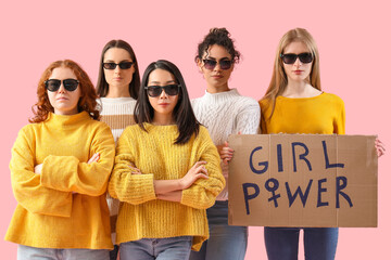 Beautiful young women in sunglasses holding paper with text GIRL POWER on pink background. Women...