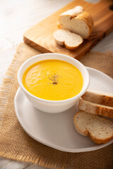 Homemade carrot and pumpkin cream soup. Easy, nutritious and healthy recipe. Served in a white bowl with bread croutons. Perfect to accompany everyday food.