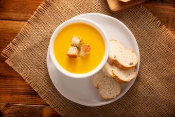 Homemade carrot and pumpkin cream soup. Easy, nutritious and healthy recipe. Served in a white bowl with bread croutons. Perfect to accompany everyday food.