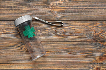 Sports bottle with clover on wooden background. St. Patrick's Day celebration