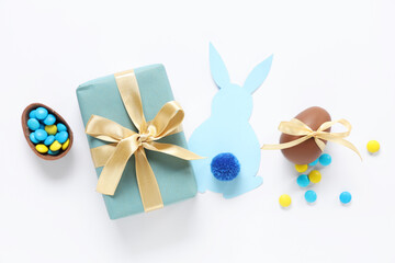 Obraz na płótnie Canvas Sweet chocolate Easter eggs with candies, gift box and bunny made of paper on white background