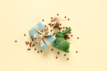 Sweet chocolate Easter egg with candies, gift box and bunny on yellow background