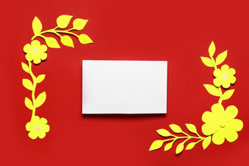 Blank card with yellow paper flowers and leaves on red background