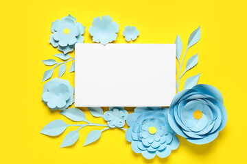 Blank card with blue origami flowers and leaves on yellow background