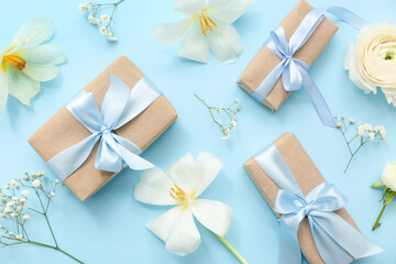 Elegant composition with wrapped gift boxes and spring flowers on cyan background