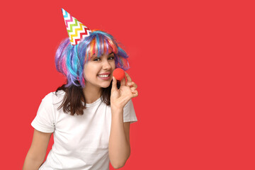 Beautiful young woman in funny disguise on red background. April fool's day celebration