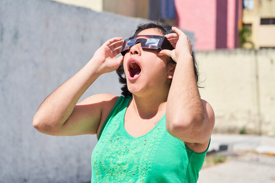 Happy young latina woman with solar eclipse glasses, watching a solar eclipse