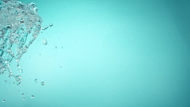 Super Slow Motion of Flying Water Splashes, Isolated on Blue Background. Filmed on High Speed Cinema Camera, 1000fps.