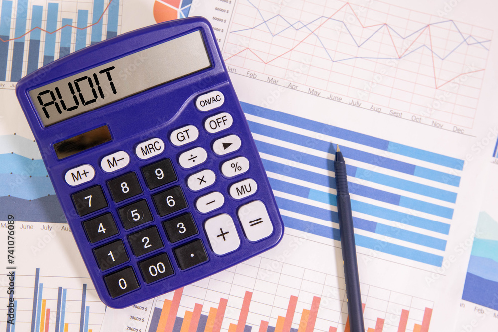 Poster audit text on the white paper on light background with charts paper ,keyboard and calculator