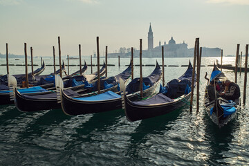 Gondolas docked at San Marco Canal with San Giorgio Maggiore island in the background in Venice,...