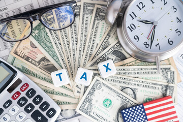 Time to pay taxes. Word TAXES on the background of banknotes and tax forms and tables.