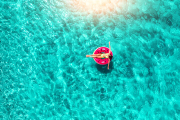 Aerial view of a woman swimming with red swim ring in blue sea
