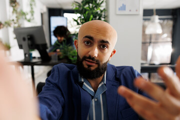 Executive manager looking at camera while presenting project during video call on smartphone. Arab startup entrepreneur holding mobile phone and explaining strategy in online meeting