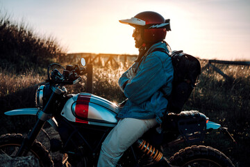 Chico moreno con moto tipo scrambler en la playa viajando 